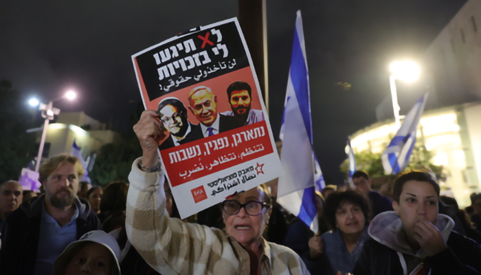 Donna tiene in mano un manifesto contro il governo israeliano